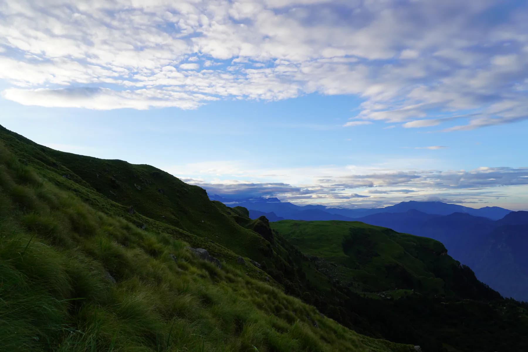 Green alpine ridge and layered mountain valleys on the Chandrashila route