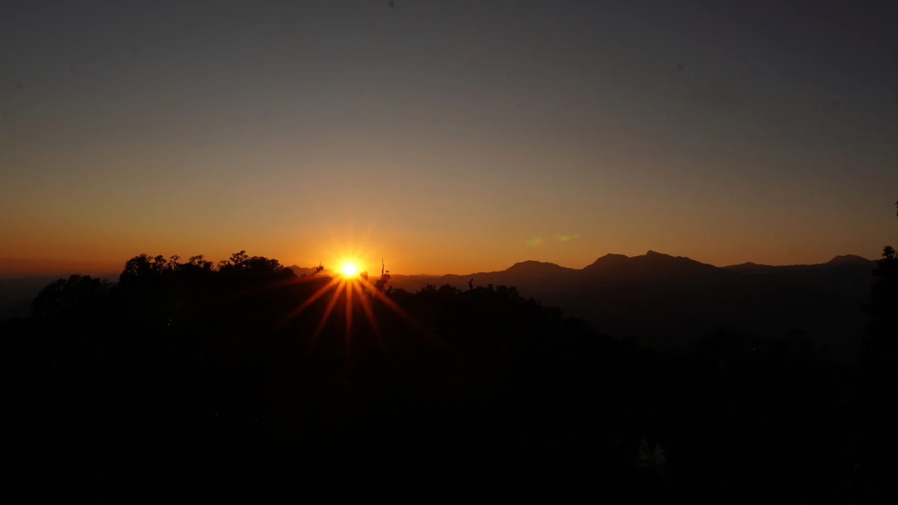 Sunrise breaking above a dark Himalayan ridgeline near Deoriatal