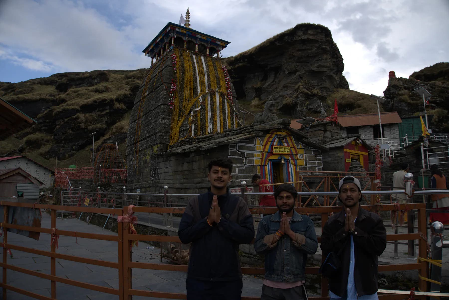 Three trekkers standing in front of Tungnath Temple in Uttarakhand