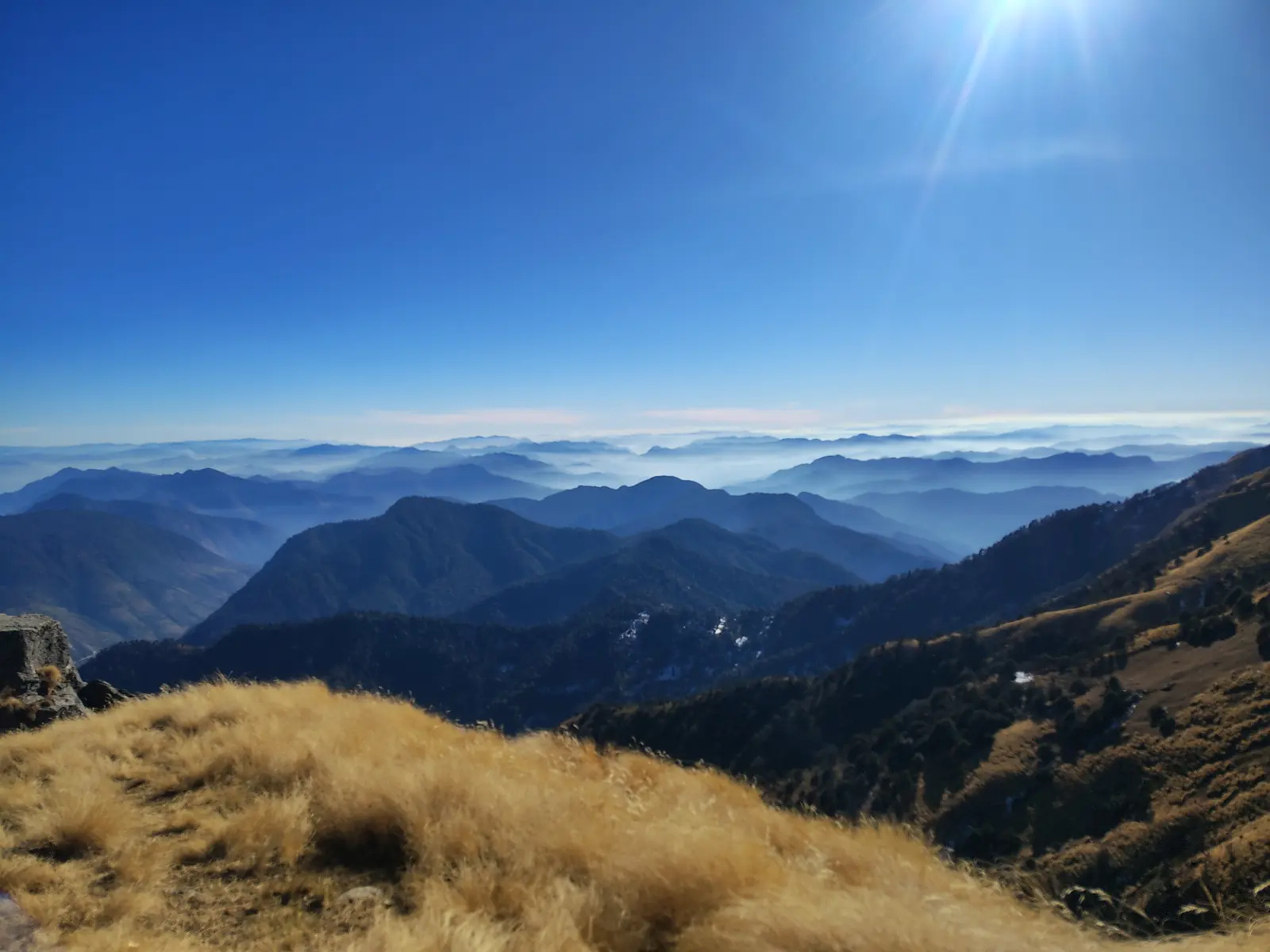 Golden Khaliya bugyal slopes above distant blue mountain ridges