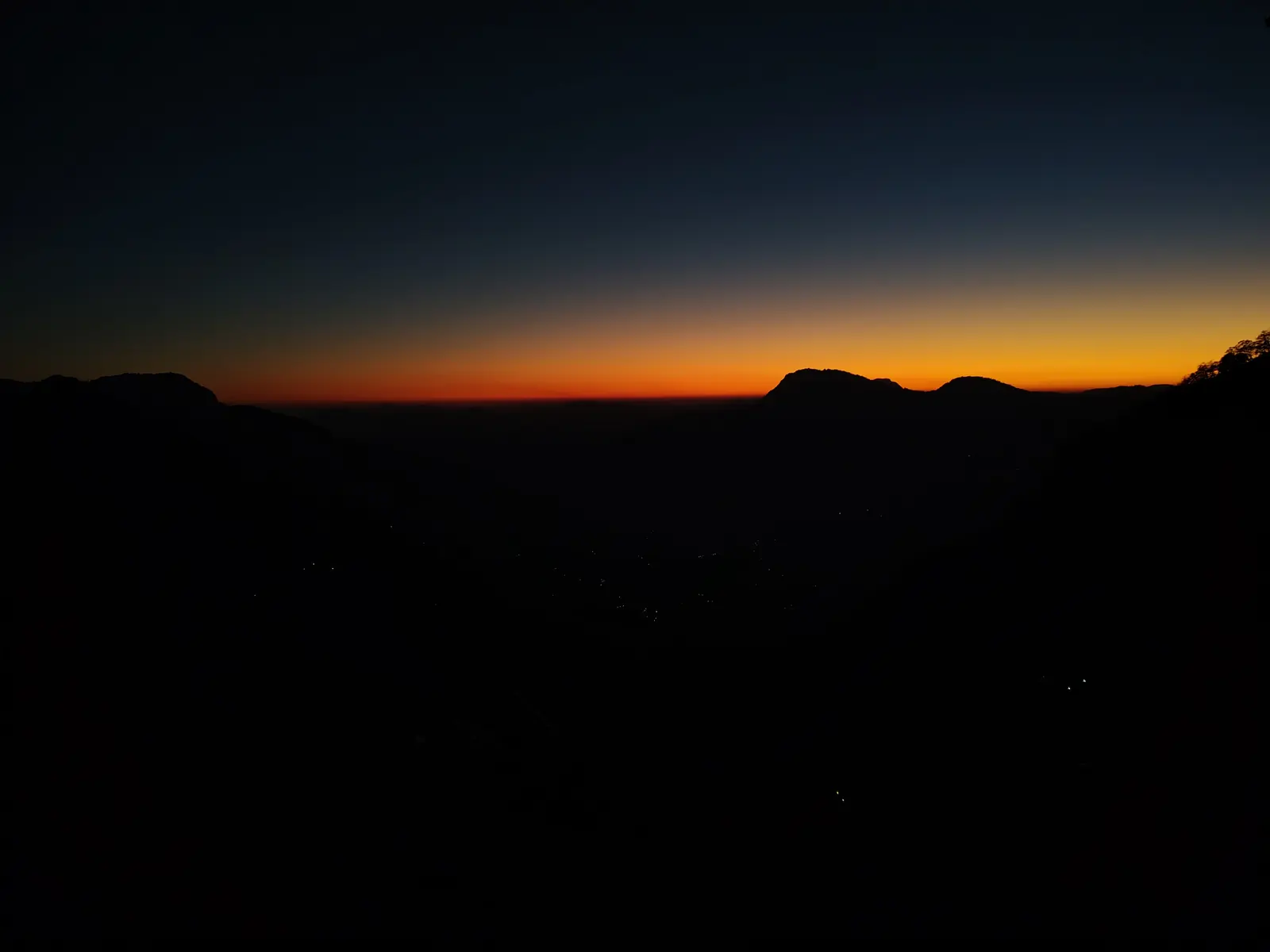 Orange sunset band behind dark mountain ridges near Munsyari